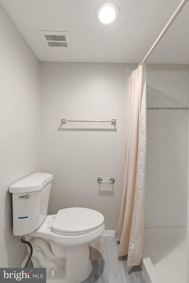 bathroom with wood-type flooring, toilet, and walk in shower