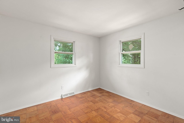 spare room featuring light parquet floors and a wealth of natural light