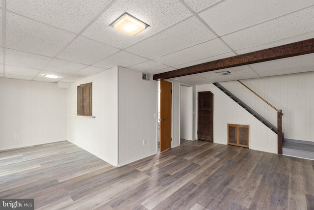 basement featuring wood-type flooring and a paneled ceiling