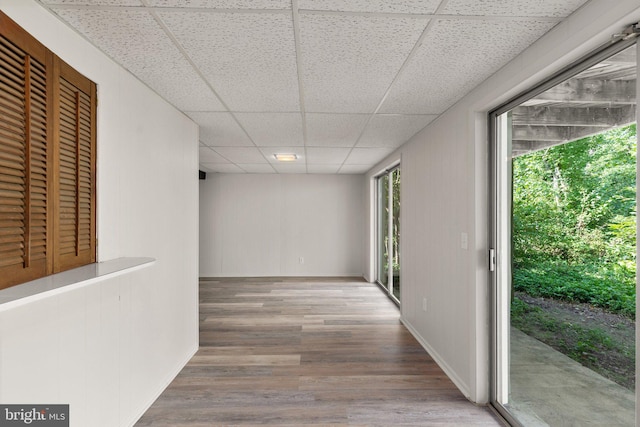 hall with a paneled ceiling and wood-type flooring