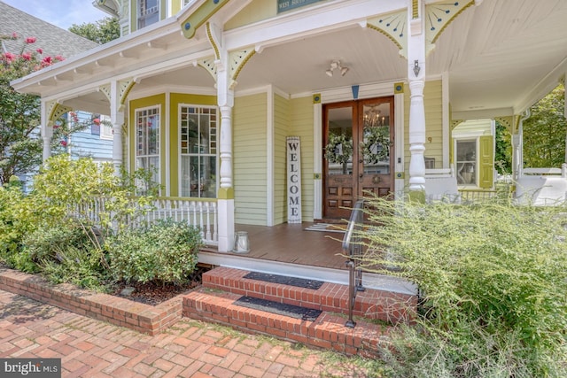 view of exterior entry featuring french doors and covered porch