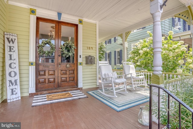 view of exterior entry featuring french doors and covered porch