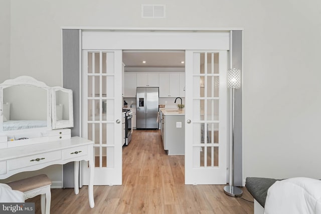 bedroom with stainless steel fridge, french doors, sink, and light hardwood / wood-style floors