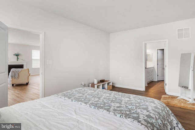 bedroom with ensuite bath and wood-type flooring