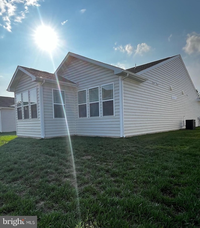 view of side of property with a yard and cooling unit