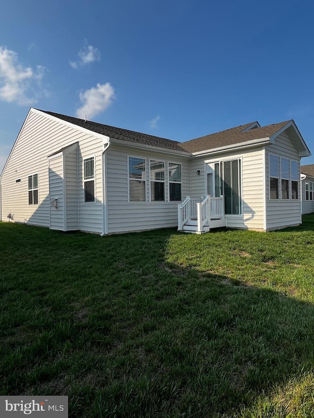 rear view of property featuring a lawn