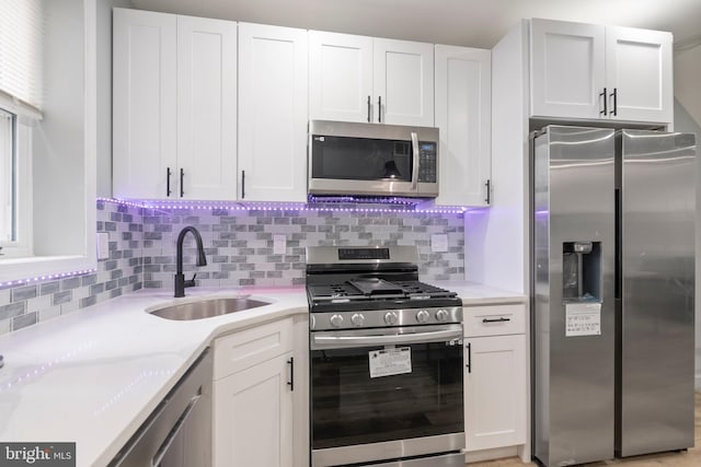 kitchen with light stone countertops, appliances with stainless steel finishes, sink, and white cabinets