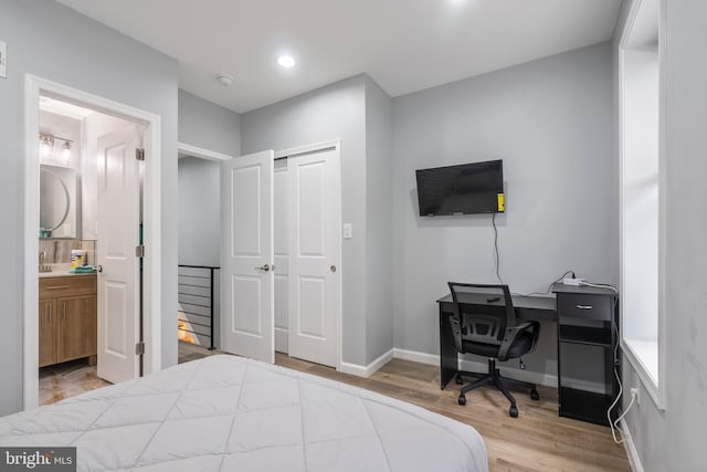 bedroom featuring hardwood / wood-style flooring, ensuite bath, and a closet