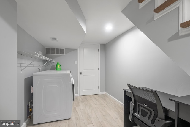 clothes washing area featuring separate washer and dryer and light hardwood / wood-style floors