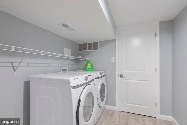 washroom with separate washer and dryer and light hardwood / wood-style floors