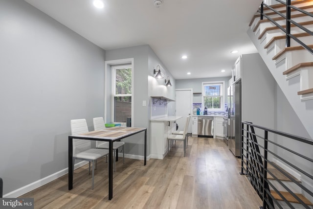 kitchen featuring stainless steel appliances, a kitchen breakfast bar, light wood-type flooring, and white cabinets