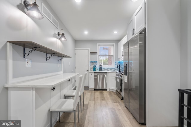 kitchen featuring white cabinetry, tasteful backsplash, light hardwood / wood-style floors, and appliances with stainless steel finishes