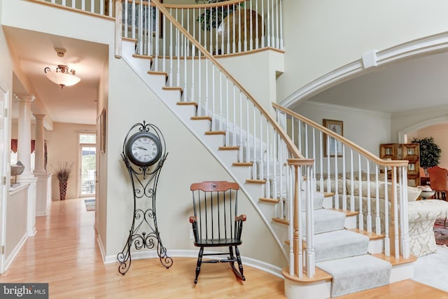 stairway featuring crown molding, decorative columns, and hardwood / wood-style flooring