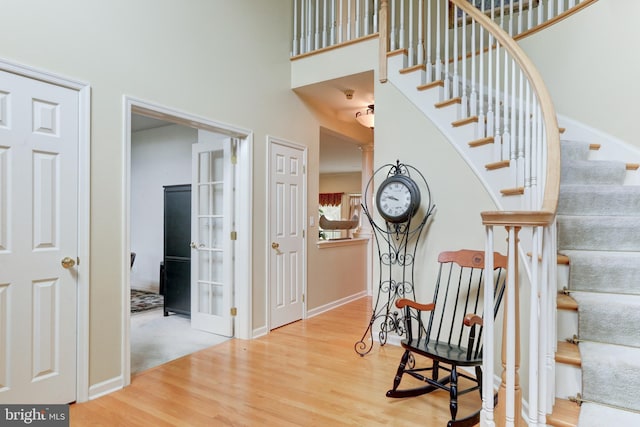 staircase featuring wood-type flooring and a towering ceiling