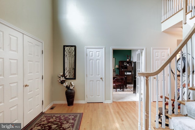 entryway featuring a high ceiling, baseboards, stairway, and wood finished floors