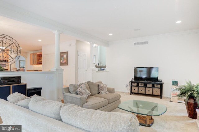 carpeted living room with crown molding and decorative columns