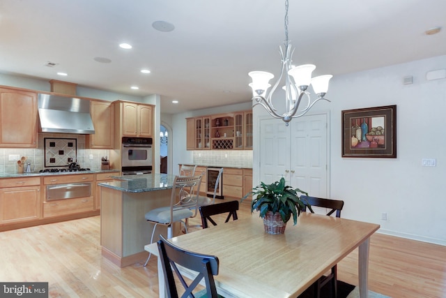 dining room with light wood-type flooring, beverage cooler, and a notable chandelier