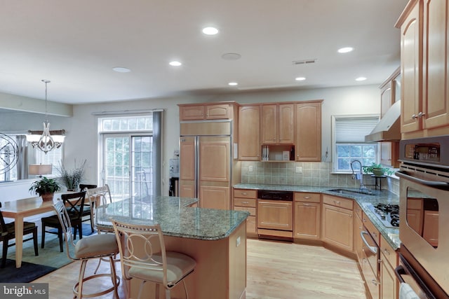 kitchen featuring light hardwood / wood-style floors, paneled appliances, a center island, decorative light fixtures, and a notable chandelier