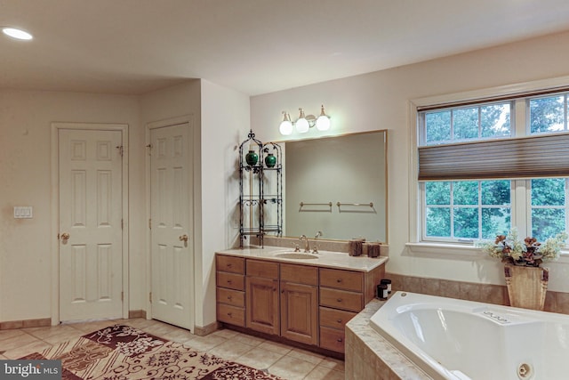 bathroom with tiled tub, vanity, and tile patterned flooring