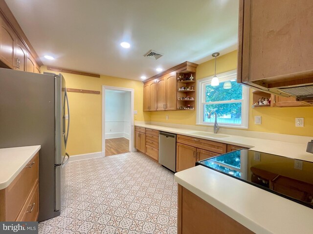 kitchen with light tile patterned floors, appliances with stainless steel finishes, sink, and decorative light fixtures