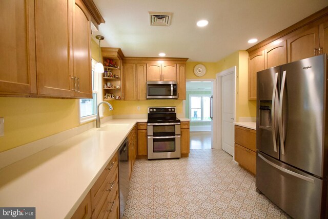 kitchen with sink, stainless steel appliances, decorative light fixtures, and light tile patterned floors