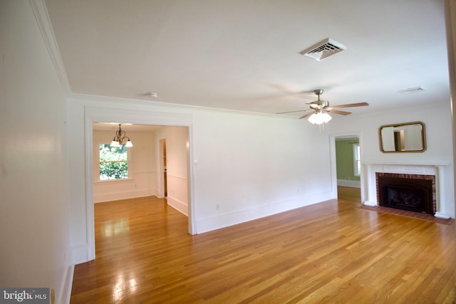 unfurnished living room with a fireplace, light hardwood / wood-style flooring, ceiling fan with notable chandelier, and ornamental molding