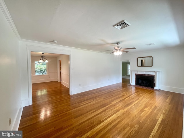 unfurnished living room featuring hardwood / wood-style flooring, a fireplace, crown molding, and ceiling fan with notable chandelier