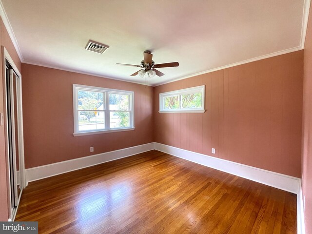 unfurnished bedroom with a closet, ceiling fan, crown molding, and hardwood / wood-style flooring