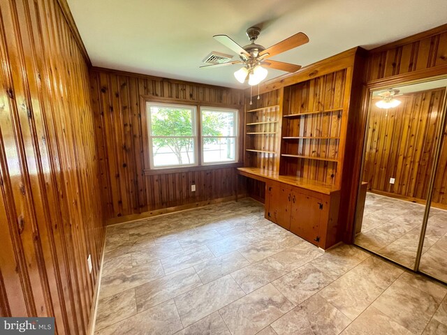 interior space with light tile patterned flooring, ceiling fan, and wooden walls