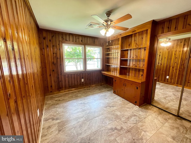 unfurnished office with built in desk, visible vents, and wooden walls