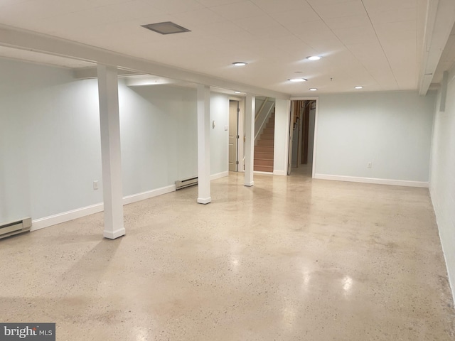 finished below grade area featuring a baseboard heating unit, stairway, and baseboards