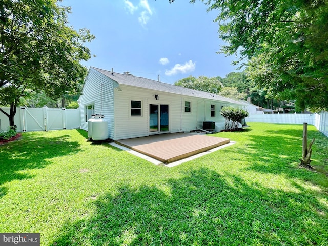 rear view of house with cooling unit, a fenced backyard, a yard, a wooden deck, and a gate