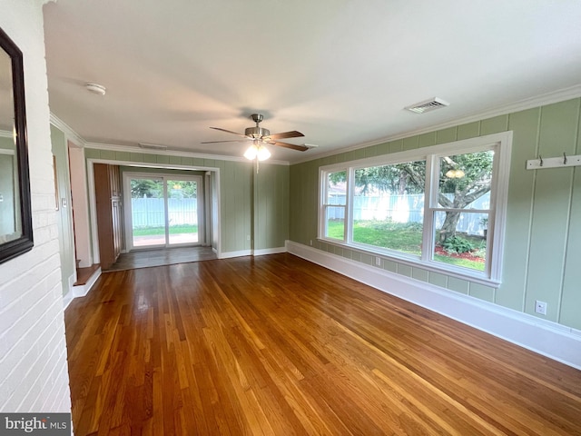 unfurnished room with ornamental molding, visible vents, ceiling fan, and wood finished floors