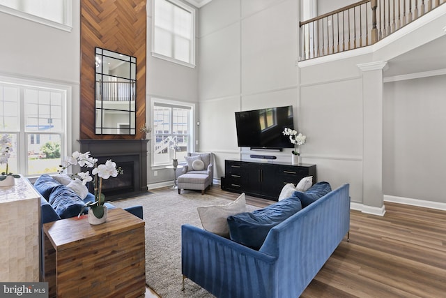 living area with a fireplace with flush hearth, a high ceiling, baseboards, and dark wood-type flooring