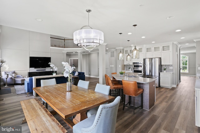 dining area featuring dark wood-style floors, decorative columns, a chandelier, and recessed lighting