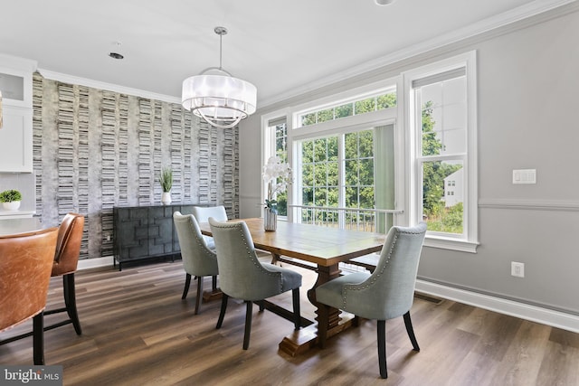 dining space featuring baseboards, dark wood-type flooring, crown molding, and a chandelier