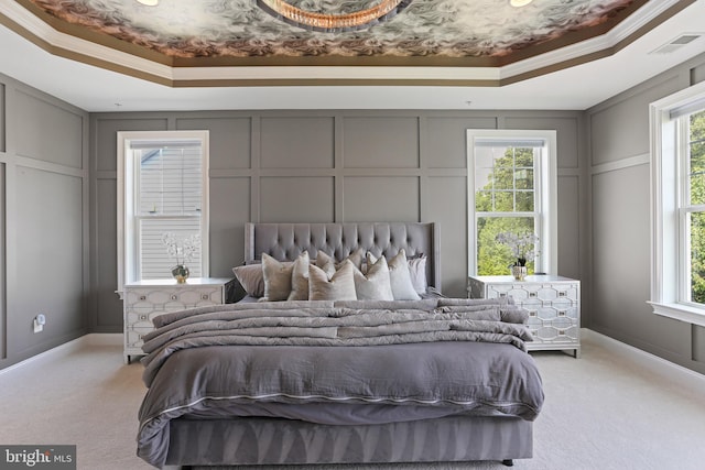 bedroom with a tray ceiling, visible vents, and a decorative wall