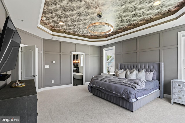 bedroom with ornamental molding, a tray ceiling, light carpet, and a decorative wall