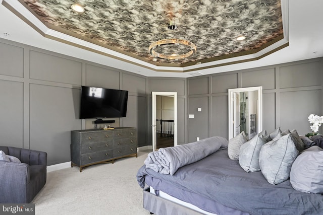 bedroom featuring light carpet, ornamental molding, a raised ceiling, and a decorative wall