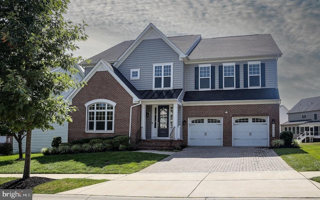 view of front of house featuring an attached garage, brick siding, decorative driveway, a front lawn, and a standing seam roof