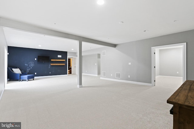 unfurnished living room with baseboards, visible vents, and light colored carpet