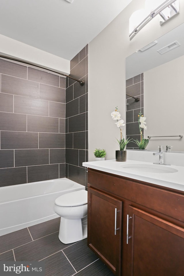 bathroom with visible vents, toilet, vanity, and shower / tub combination