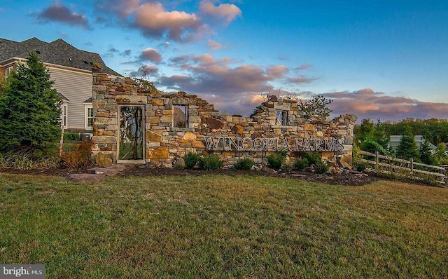 exterior space with stone siding, a lawn, and fence