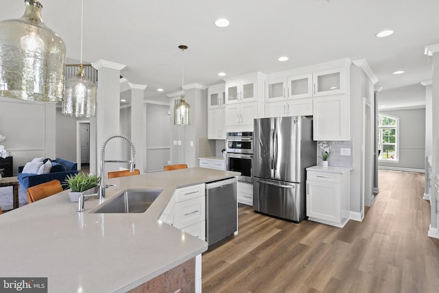 kitchen featuring glass insert cabinets, stainless steel appliances, a sink, and light countertops