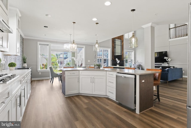 kitchen featuring stainless steel appliances, a kitchen island with sink, pendant lighting, and white cabinets