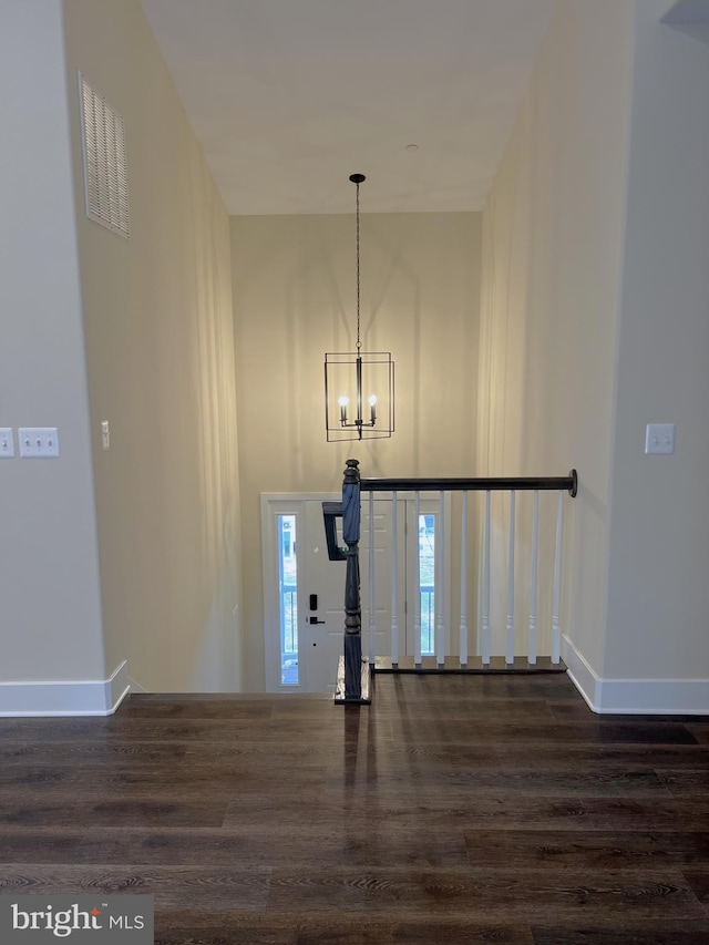 entryway featuring dark wood-type flooring and an inviting chandelier