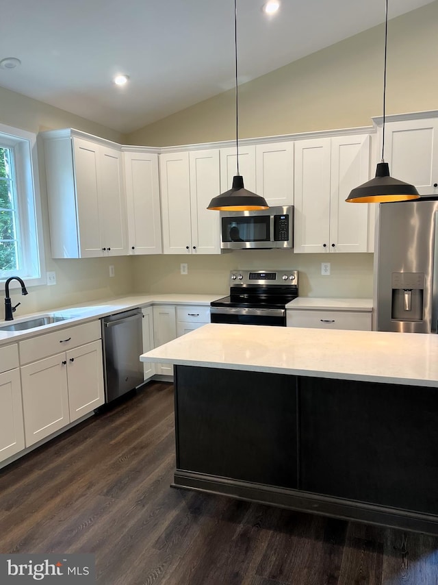 kitchen featuring vaulted ceiling, white cabinetry, sink, hanging light fixtures, and stainless steel appliances