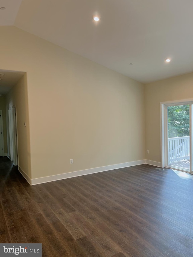 spare room with dark hardwood / wood-style flooring and lofted ceiling