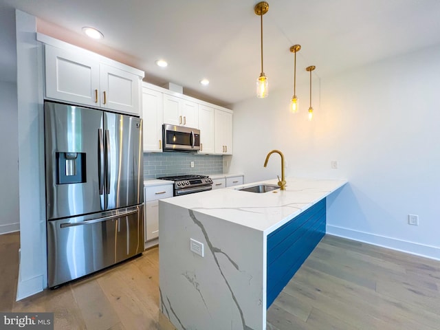 kitchen with appliances with stainless steel finishes, light hardwood / wood-style flooring, light stone countertops, and sink