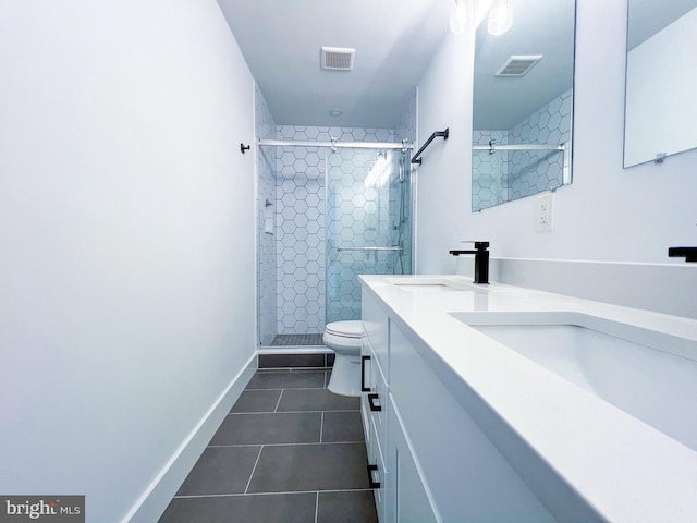 bathroom featuring dual bowl vanity, tile patterned floors, a tile shower, and toilet